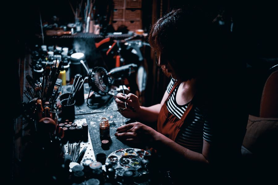 Sculptor working on a small figure under a bench lamp