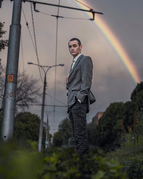 Man in a Suit Standing Against the Sky with a Rainbow