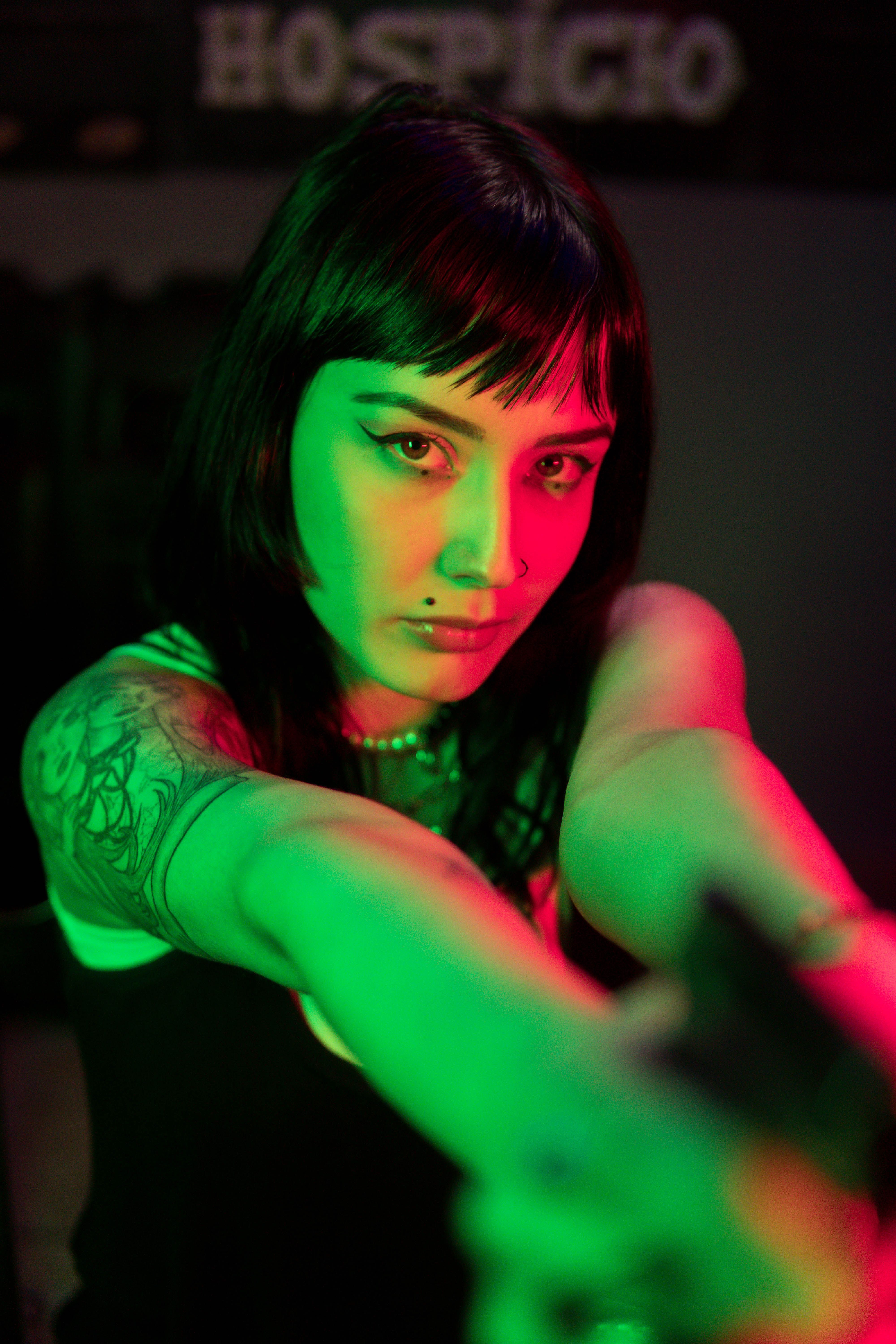 Portrait of a tattooed woman with striking colored lights, creating an edgy and artistic vibe.