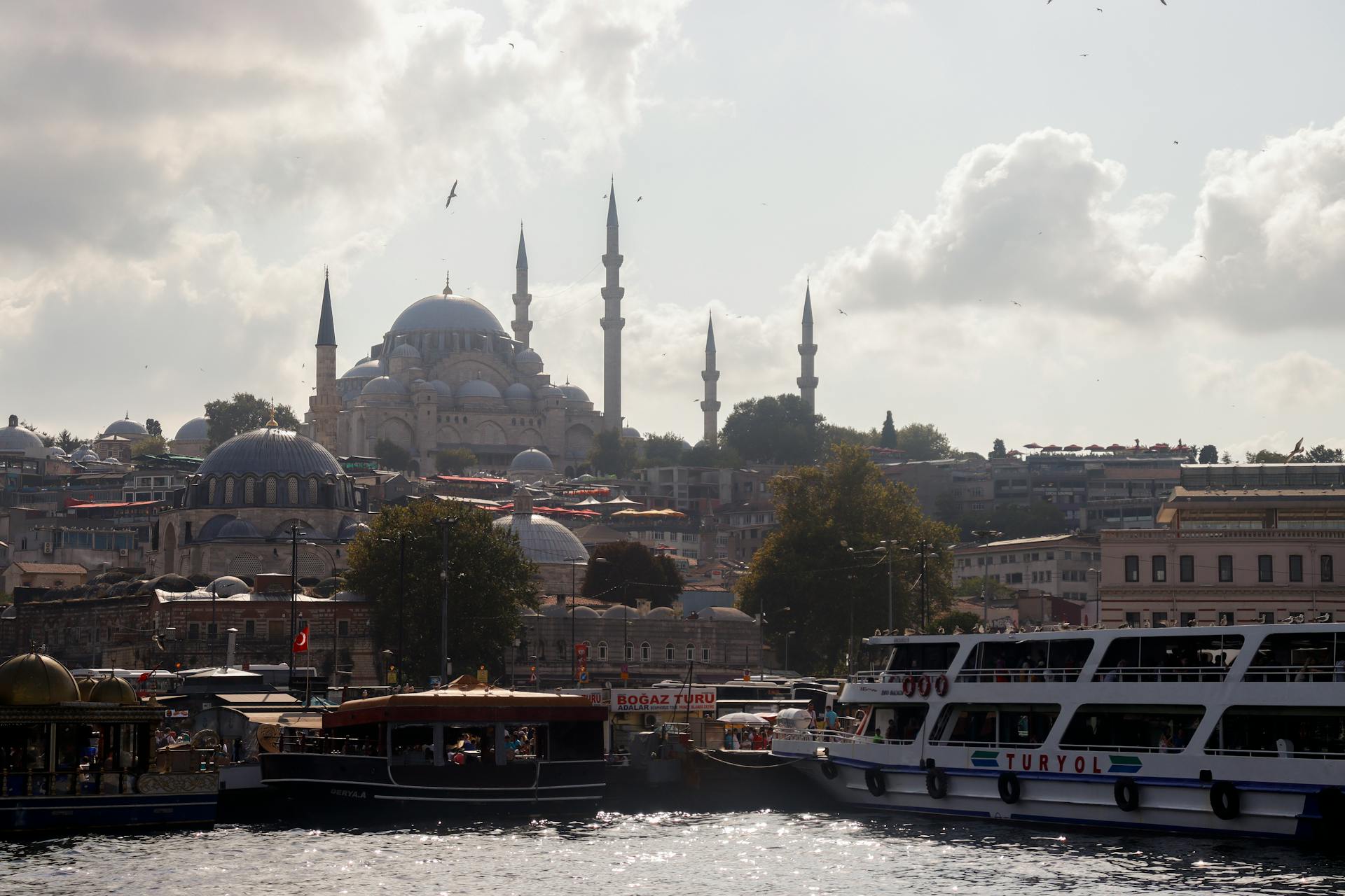 Panoramic view of Suleymaniye Mosque with boats on the Istanbul waterfront.