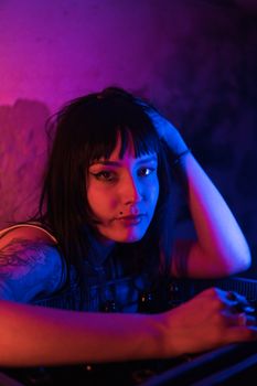 Vibrant portrait of a woman with tattoos lit by neon lights, capturing nightlife essence indoors.