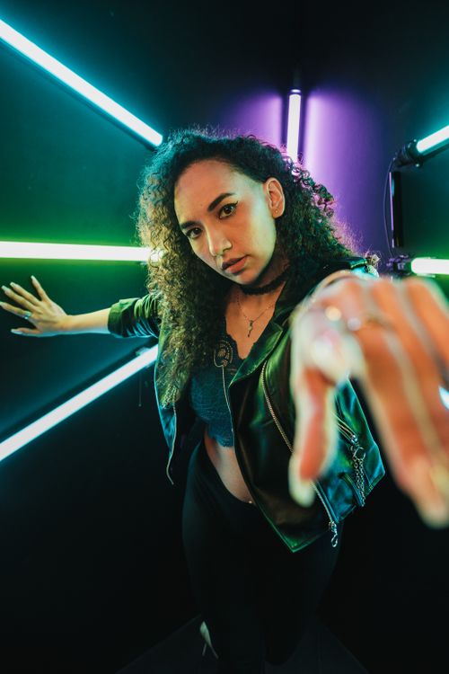 Free A stylish woman poses in a vibrant neon-lit studio, creating a moody and dynamic atmosphere. Stock Photo