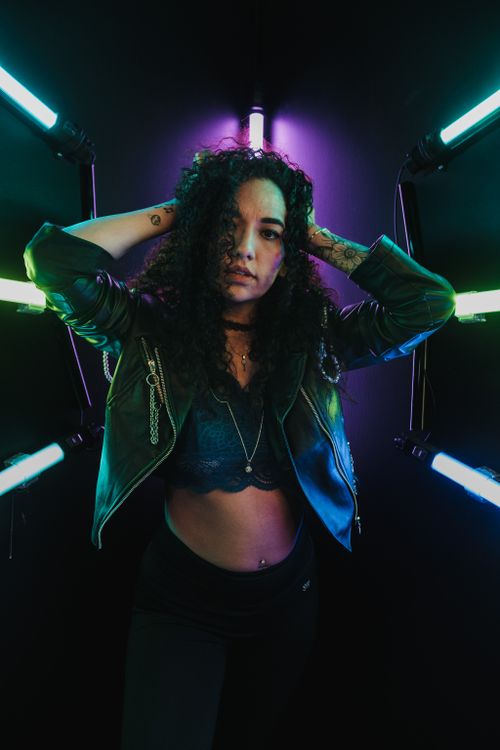 Free Dynamic portrait of a woman with curly hair surrounded by vibrant neon lights. Stock Photo