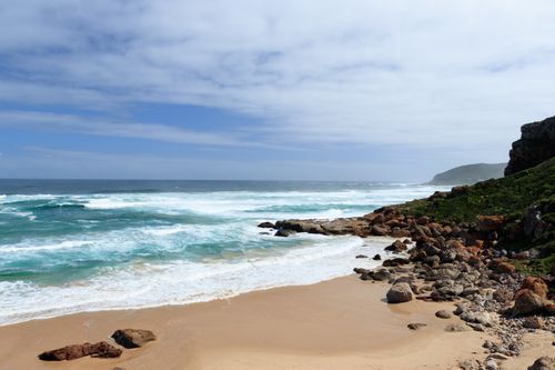 Free A stunning view of a rocky beach with turquoise waves under a bright blue sky, perfect for nature and travel enthusiasts. Stock Photo
