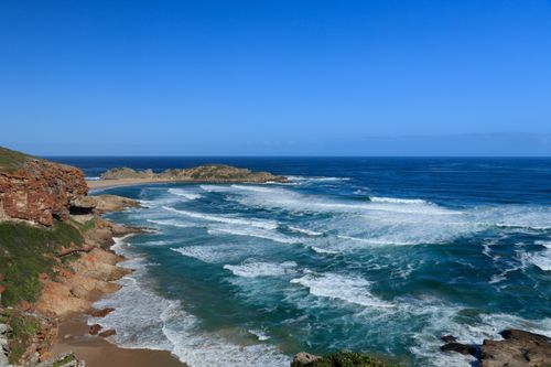 Free Enjoy a breathtaking coastal view featuring waves crashing over rocky shores under a clear blue sky. Stock Photo