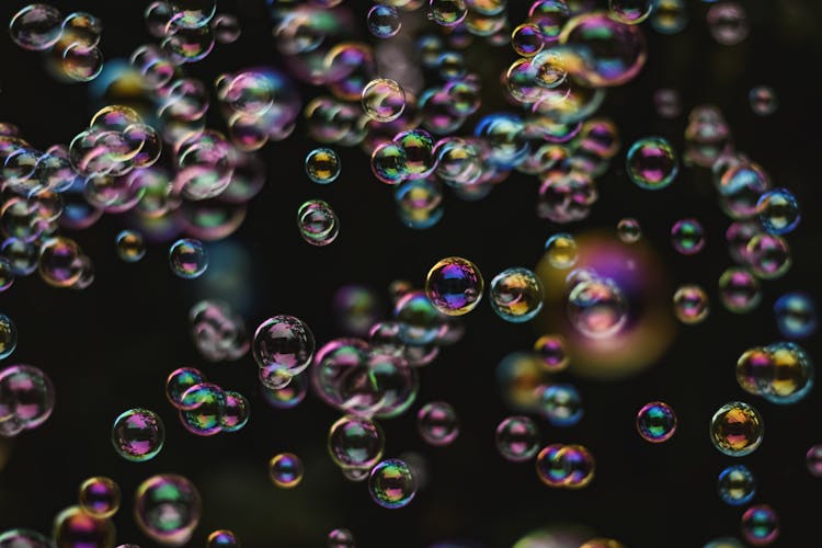 A Bunch Of Bubbles Floating On Dark Background