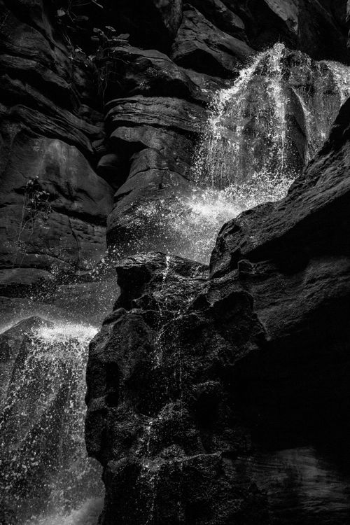 Free Dramatic black and white photo of a waterfall in rock formations. Stock Photo