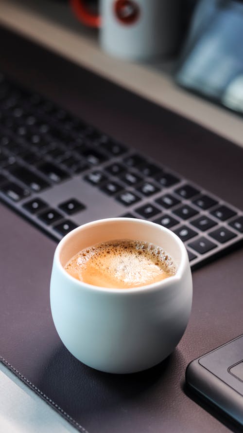 Cup of Coffee Beside a Computer Keyboard