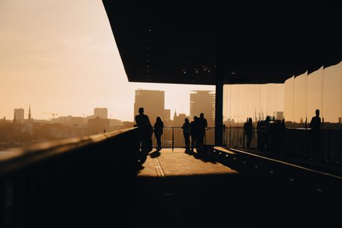 Free Silhouetted people on a balcony overlooking Hamburg skyline at sunset, creating a serene urban scene. Stock Photo