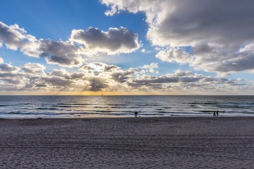 Free A peaceful beach scene with a stunning sunset and dramatic cloud formations. Stock Photo