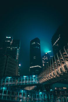 A stunning night view of a modern cityscape with illuminated skyscrapers and architectural structures.