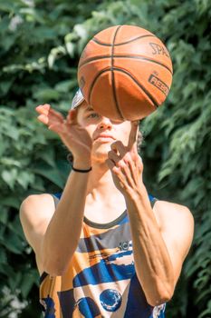 Athletic young man spinning a basketball on his finger outdoors in daylight.