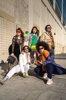 A stylish group of diverse individuals striking a pose outdoors, showcasing bold fashion choices.