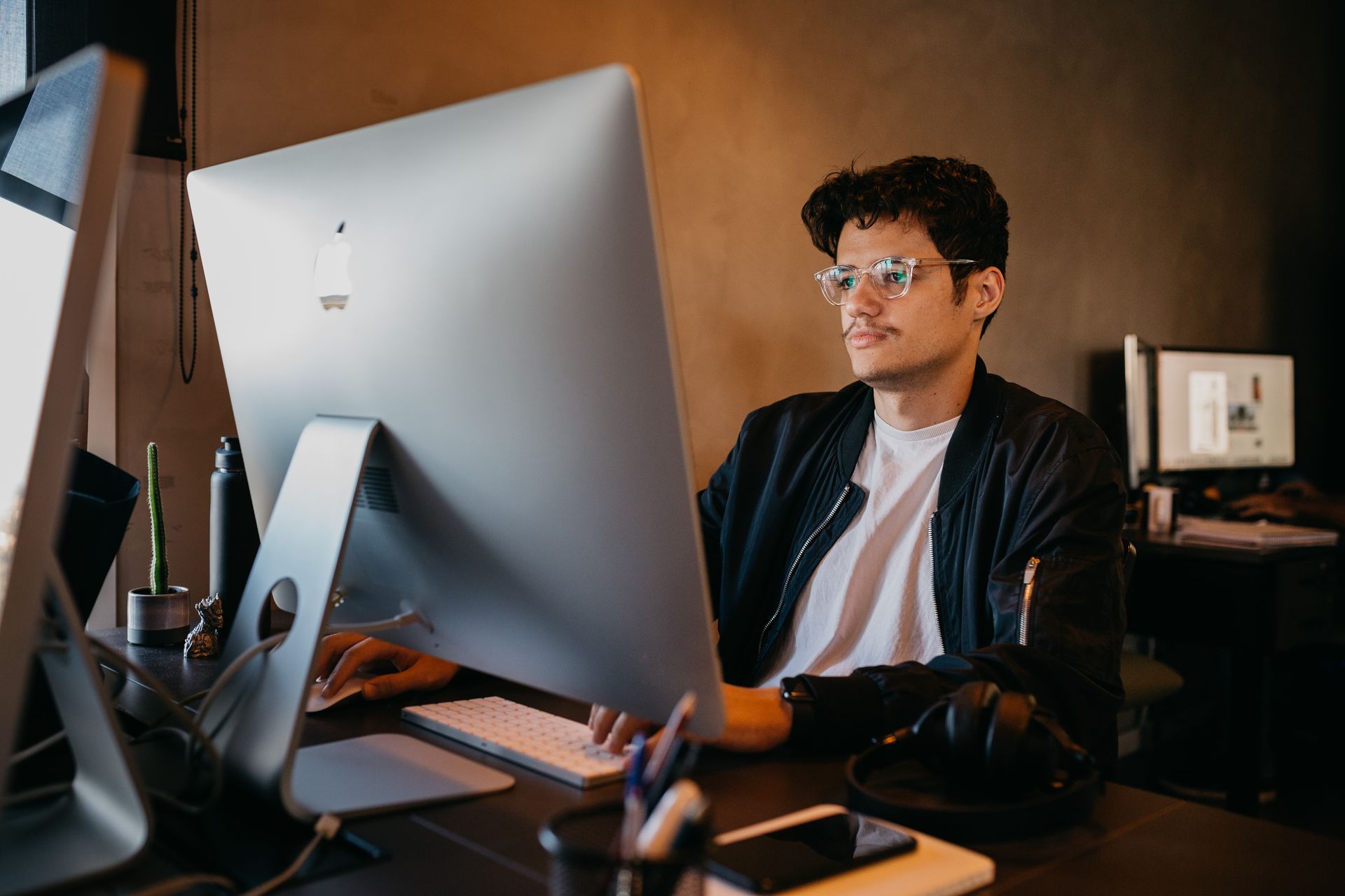 Man focused on work at a desktop computer in an office environment with modern decor.