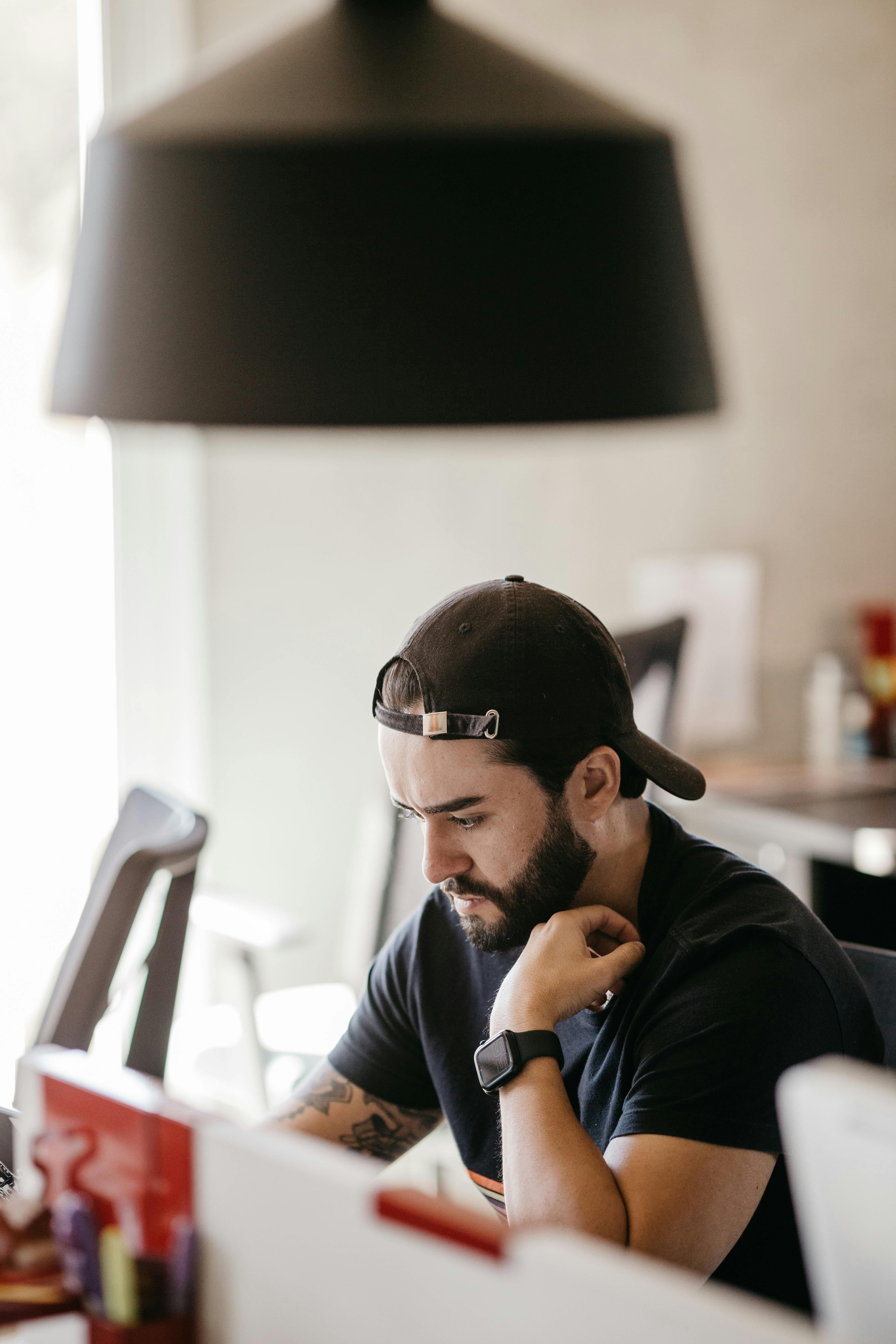 Young man concentrating on work at a computer in a modern office setting.