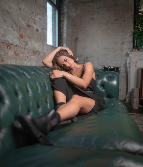 Woman in Black Dress Sitting on a Sofa