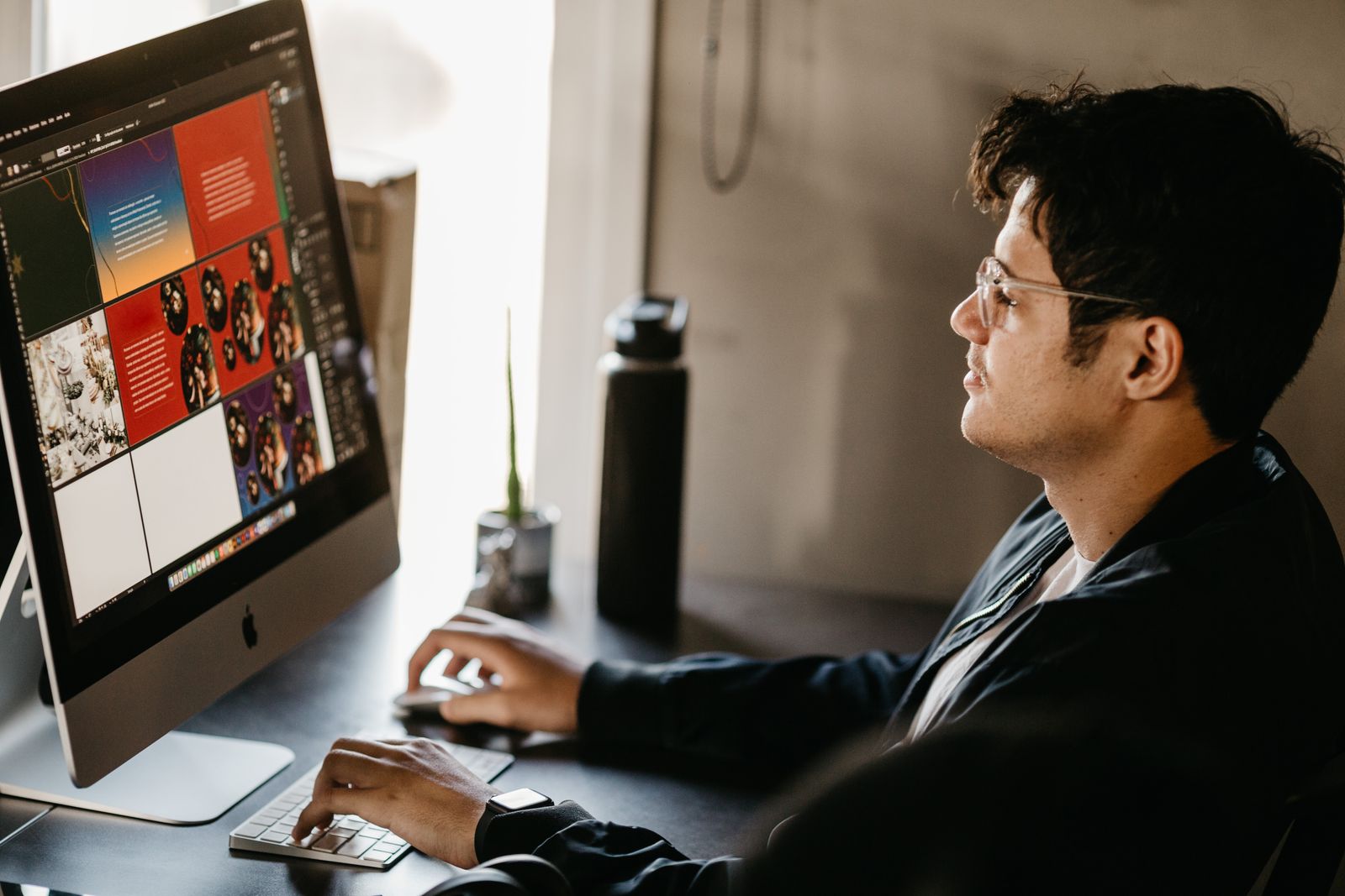 A designer working at a computer with creative visuals on screen