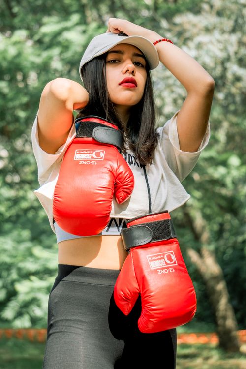 Free Confident woman posing with red boxing gloves in an outdoor setting. Stock Photo