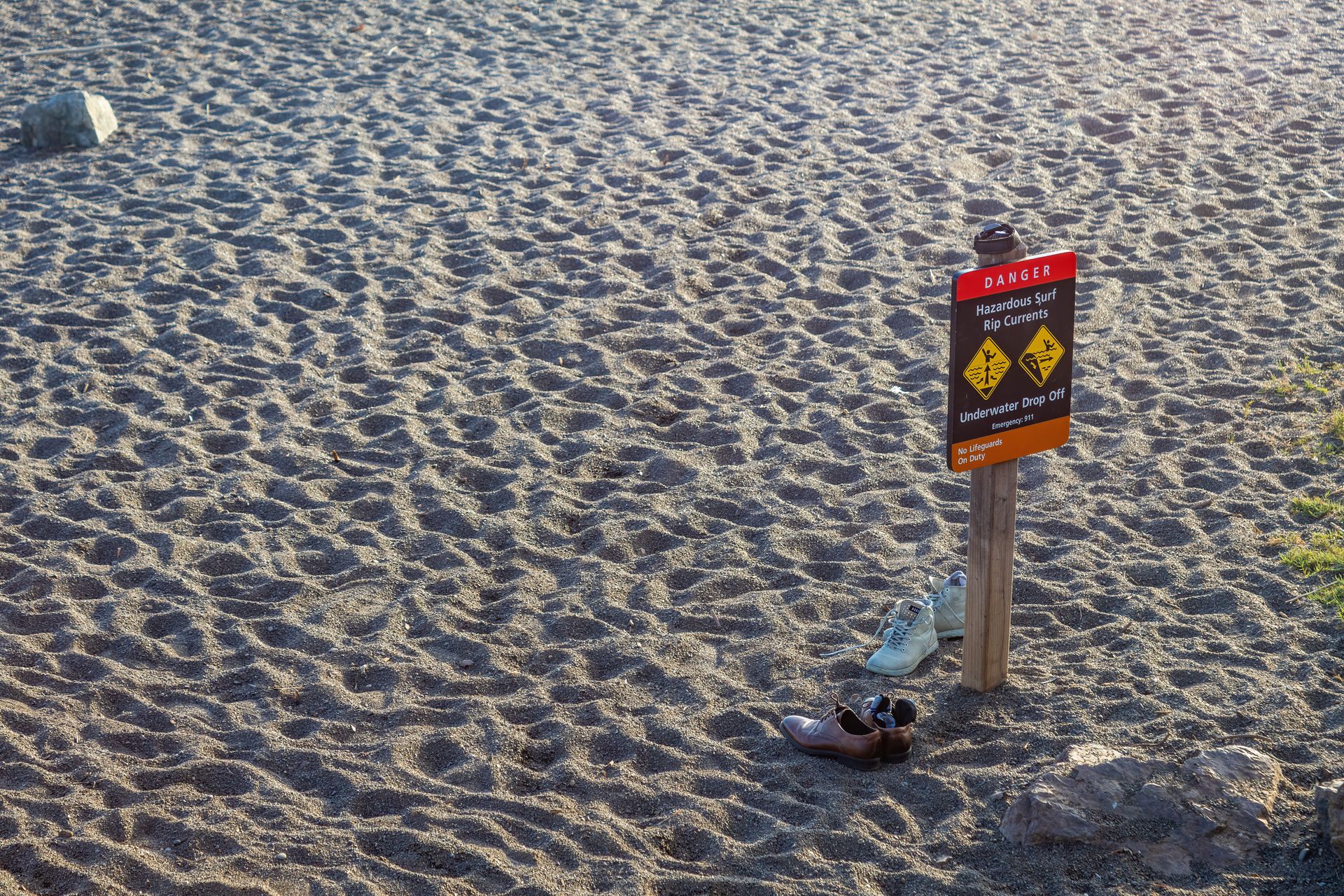 Shoes by a Warning Sign on a Beach