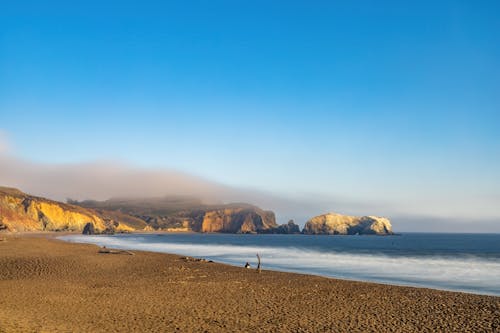 Brown Sand near Ocean under Blue Sky