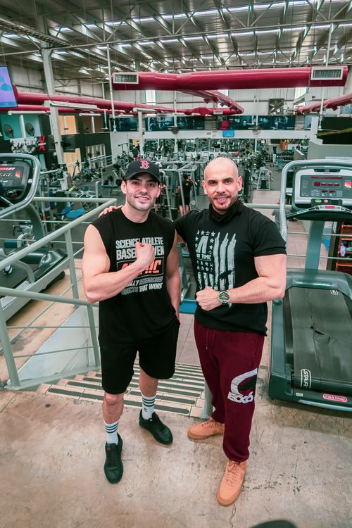 Free Two men posing and smiling in a well-equipped gym, showcasing fitness camaraderie. Stock Photo