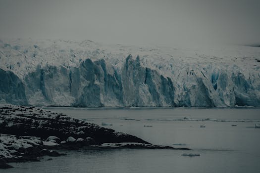 Stunning view of a vast frozen glacier landscape during winter, featuring icy formations against a serene lake.
