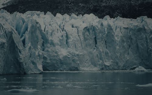 Free A breathtaking view of a massive glacier meeting the calm sea under overcast skies. Stock Photo