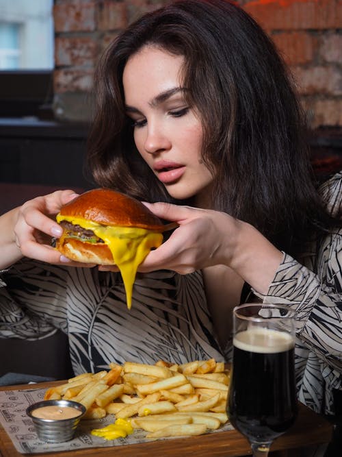 Woman in Printed Long Sleeves Eating a Burger