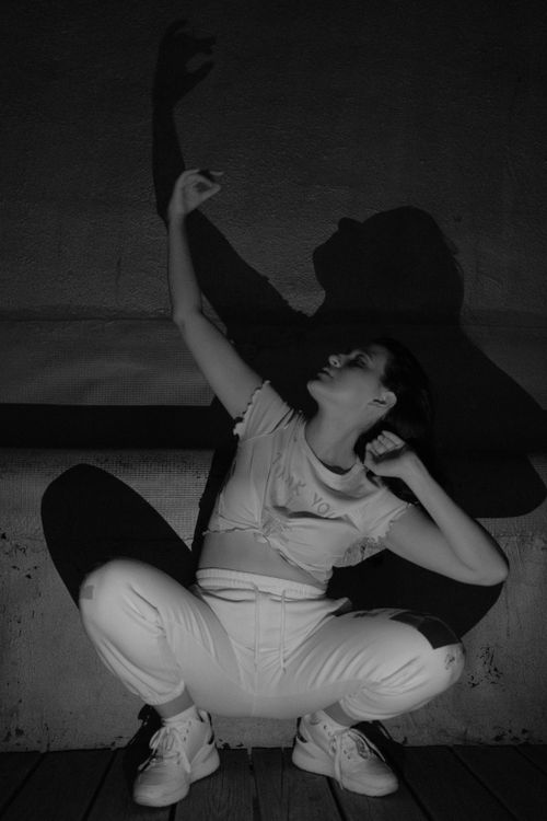 Free Artistic black and white photo of a crouching woman casting a shadow. Stock Photo
