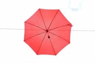 晴朗的天空中悬着一把充满活力的红色伞，形成鲜明的对比