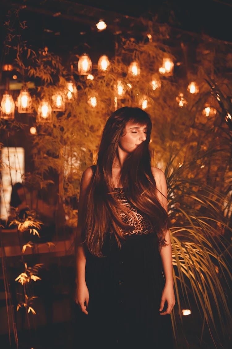 Woman Posing Outdoors In Garden With Lights