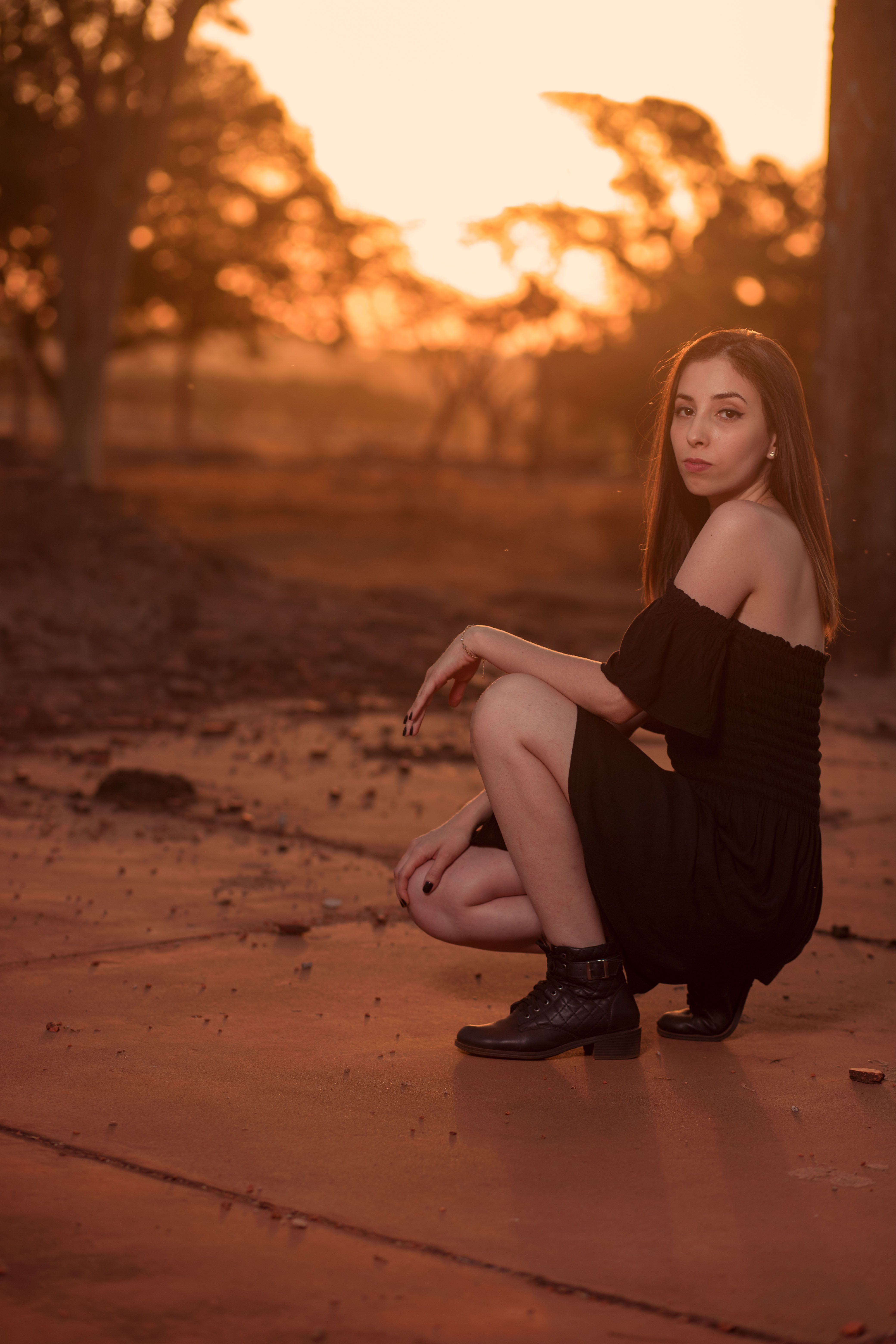 Woman in Black Dress Sitting on Concrete Pavement · Free Stock Photo