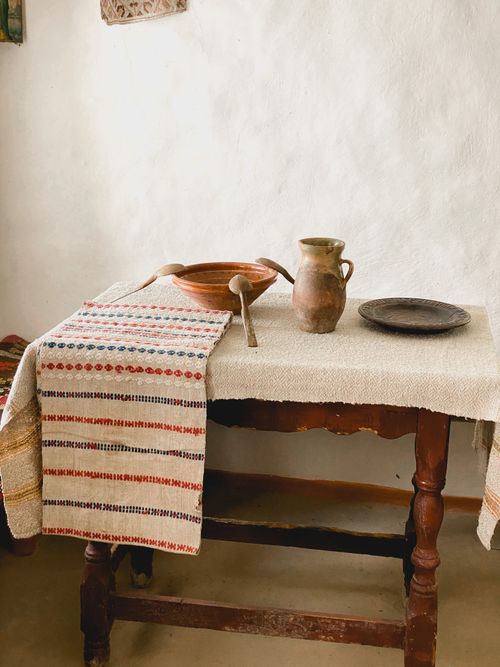 Free A rustic still life scene with a clay pot on an antique wooden table draped with a textured cloth. Stock Photo