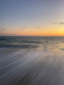 A serene view of ocean waves captured with long exposure during sunset.