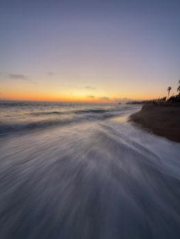 Dynamic seascape capturing waves crashing onto the shore at sunset in a vibrant display.