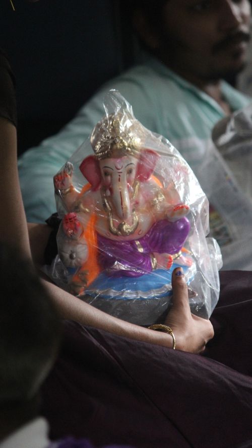 Free A handheld close-up of a vibrant Ganesh idol wrapped in plastic, highlighting religious symbolism. Stock Photo