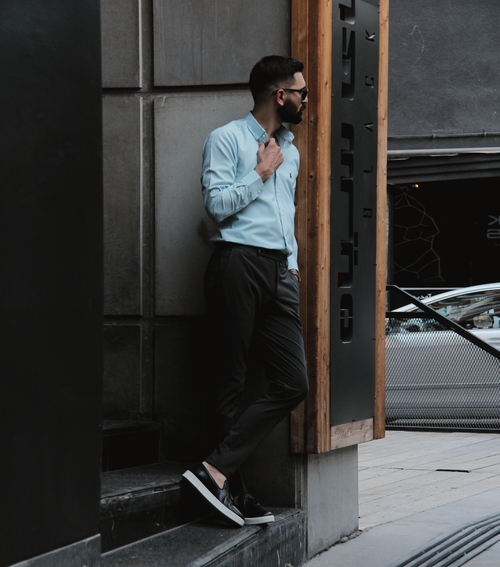 Free A fashionable man in sunglasses and blue shirt poses against a building in Tehran. Stock Photo