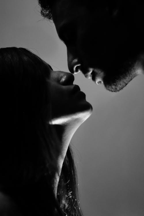 Grayscale Photo of a Man Kissing a Woman