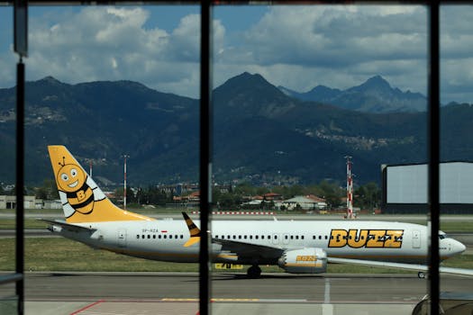 Buzz airline plane on runway at Bergamo Airport with stunning mountain backdrop.