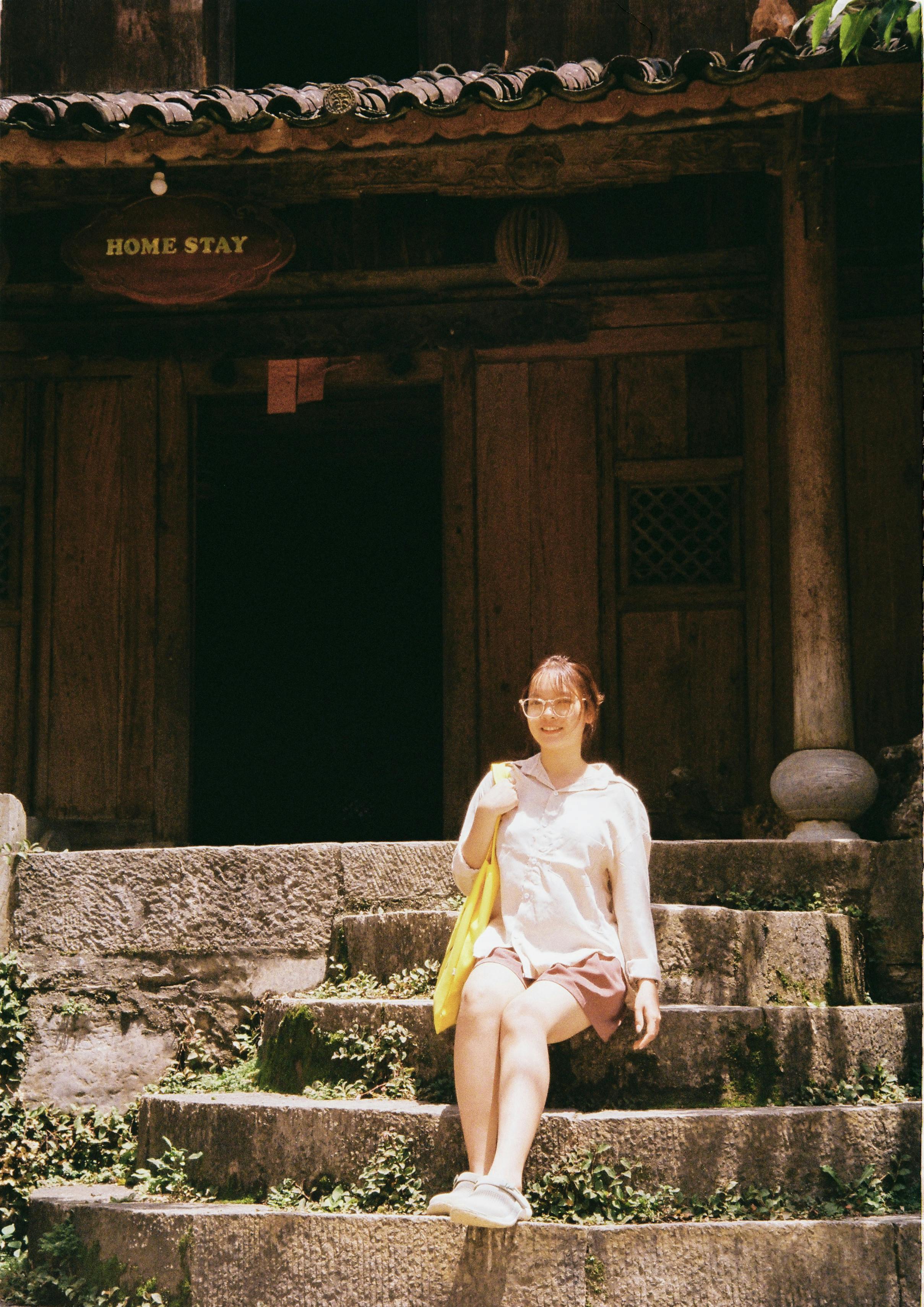 a woman sitting on the concrete stairs near the wooden house