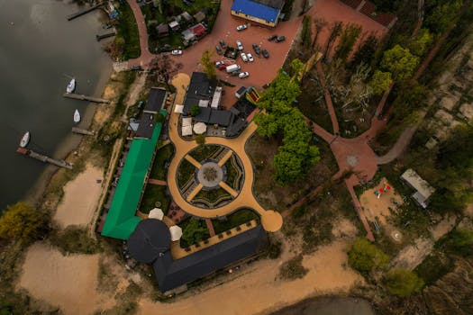 Stunning drone shot of a lakeside complex featuring a central roundabout, surrounded by nature.