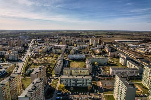 Free Aerial view of an urban residential area with buildings and green spaces on a sunny day. Stock Photo