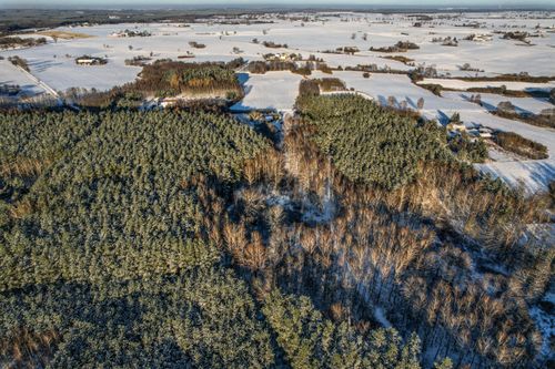 Free A stunning aerial view of a snow-covered forest and countryside landscape during winter. Stock Photo
