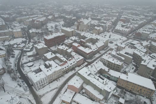 Aerial winter view of a snow-covered town with historic buildings and roads.