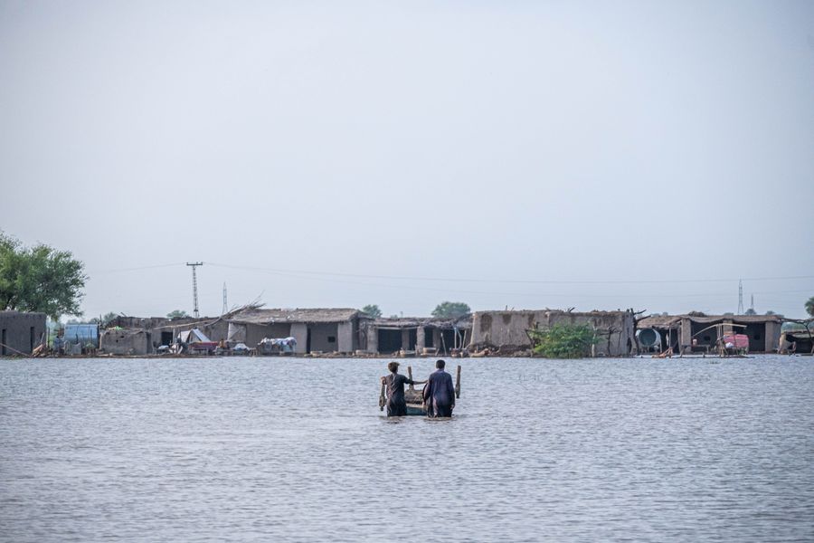 People wading through floodwater in a flood-affected community