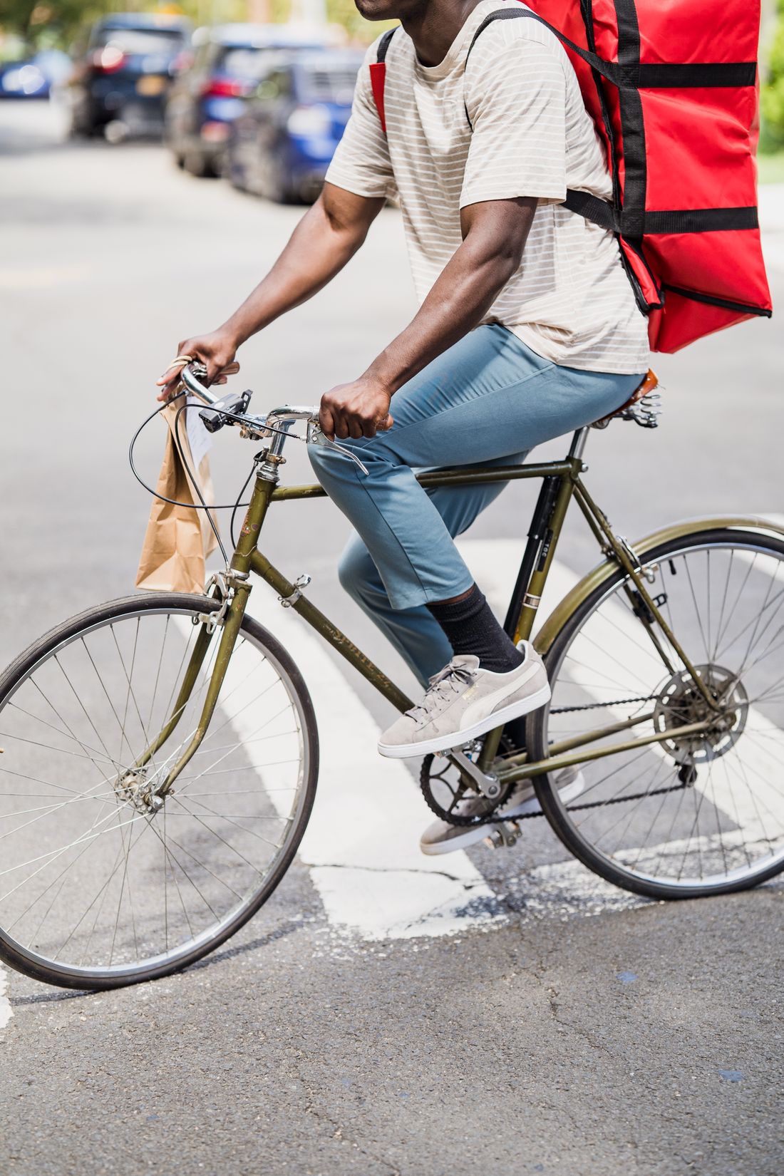 Entregador de aplicativo pedalando com a bolsa térmica na rua.