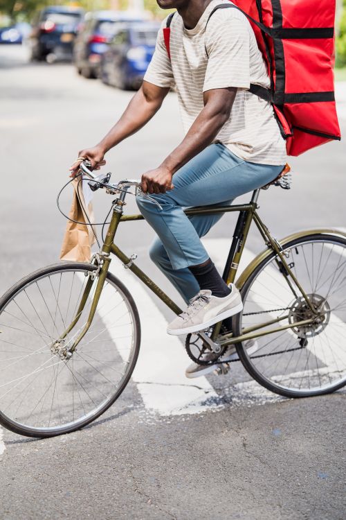 Free A man delivering food on a bicycle in an urban environment, captured during the day. Stock Photo