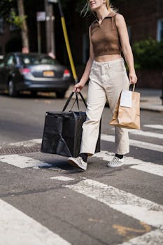 Young woman crossing city street with food delivery bags in hand.