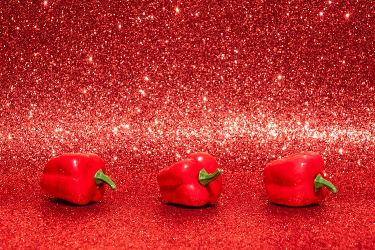 Three Red Bell Peppers On Red Surface