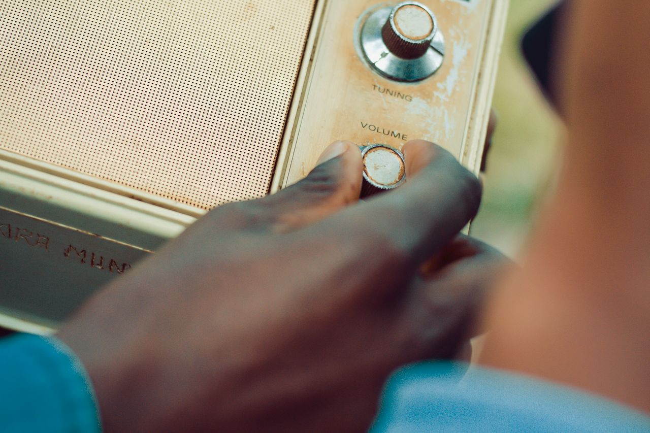 hand adjusting volume on a vintage radio in an outdoor setting